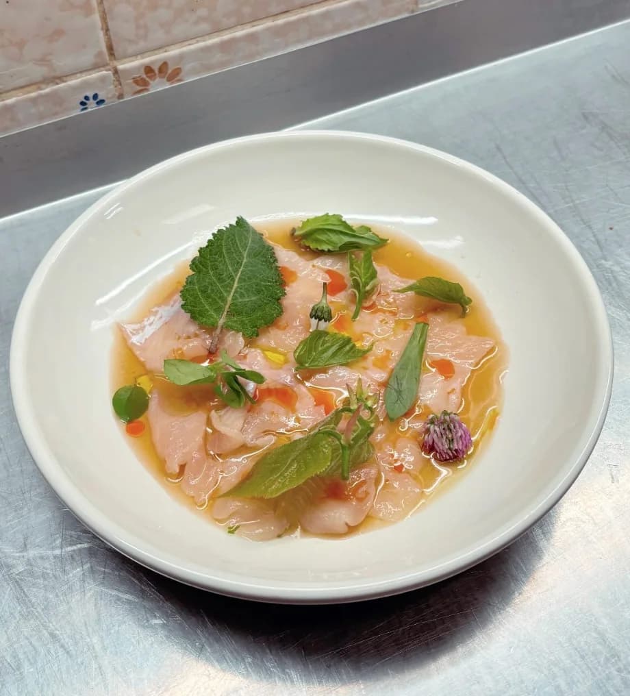 Finished seasonal crudo plate with herbs and flowers